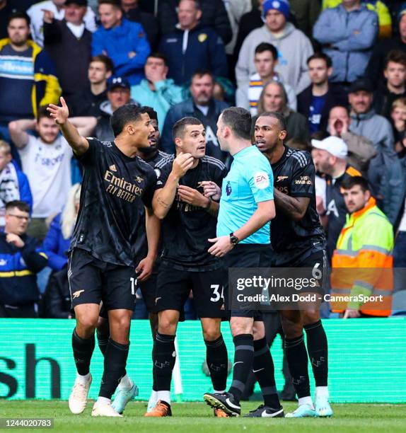 Arsenal's William Saliba, Granit Xhaka and Gabriel surround referee Chris Kavanagh after he awarded Leeds United a second penalty during the Premier...