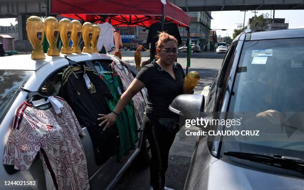 Woman sells merchandise of the Mexican national football team and FIFA trophy souvenirs in a street near the exhibition of the FIFA World Cup Trophy...