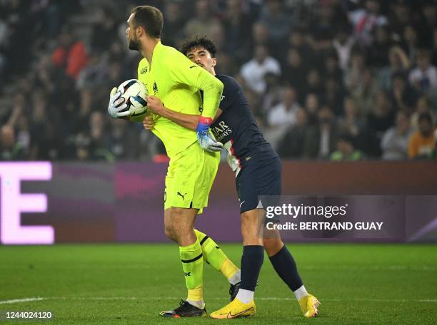 Paris Saint-Germain's Portuguese midfielder Vitinha holds Marseille's Spanish goalkeeper Pau Lopez during the French L1 football match between Paris...