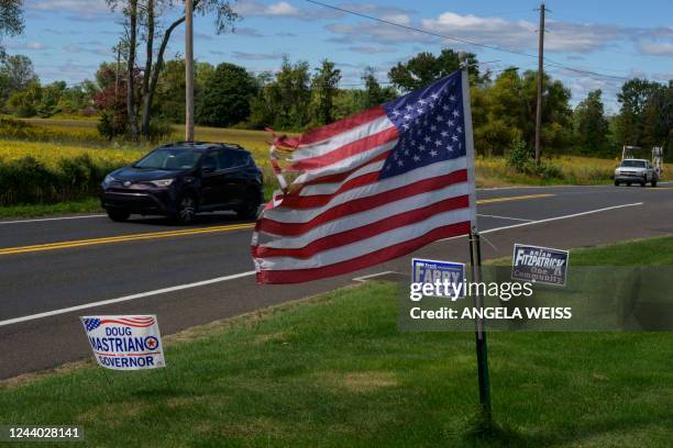 Cars drive past a front lawn with political campaign signs of Republican candiates near Doylestown, Pennsylvania on September 29, 2022. In...