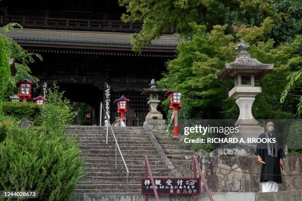 This photo taken on September 8, 2022 shows Buddhist monk Tesshu Inoue standing outside the entrance to Daizenji temple, nicknamed the "grape...