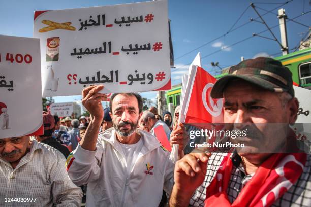 Demonstrator raises a sign that reads in Arabic, free bread, free semolina, where is the milk, as he holds Tunisian flags, during a protest march...