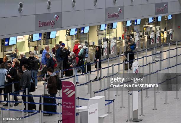 Passengers stand at the check-in counter of Eurowings airline at the Duesseldorf airport, western Germany on October 17, 2022. - Eurowings pilots...