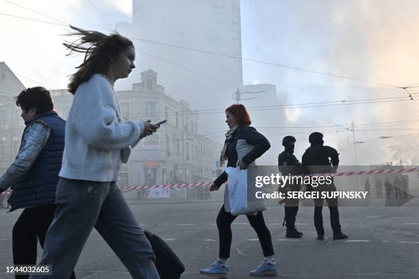 Local residents walk past police officers after a drone attack in Kyiv on October 17 amid the Russian invasion of Ukraine. - Ukraine officials said...