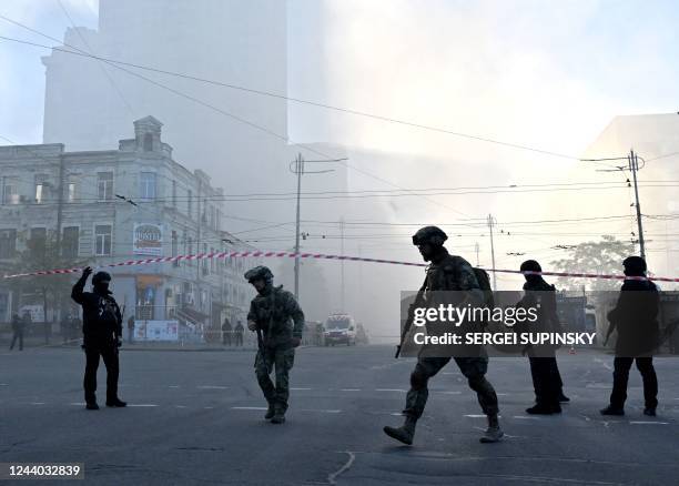 Ukrainian servicemen and police officers stand guard in a street after a drone attack in Kyiv on October 17 amid the Russian invasion of Ukraine. -...