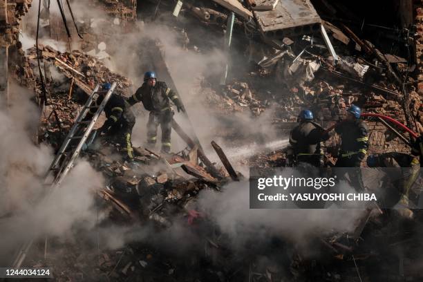 Ukrainian firefighters works on a destroyed building after a drone attack in Kyiv on October 17 amid the Russian invasion of Ukraine. - Ukraine...