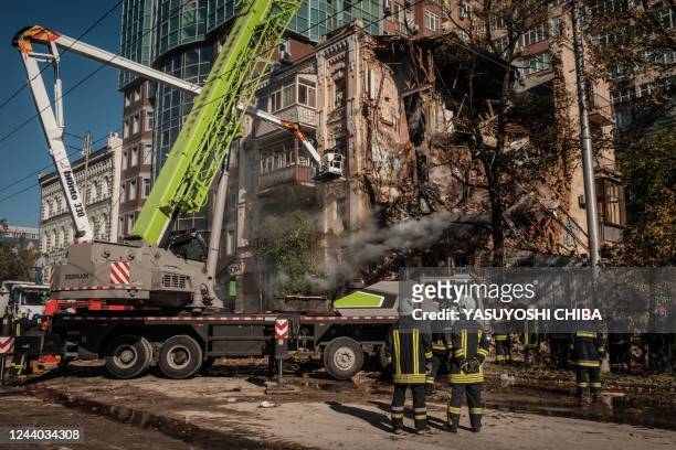 Ukrainian firefighters works on a destroyed building after a drone attack in Kyiv on October 17 amid the Russian invasion of Ukraine. - Ukraine...