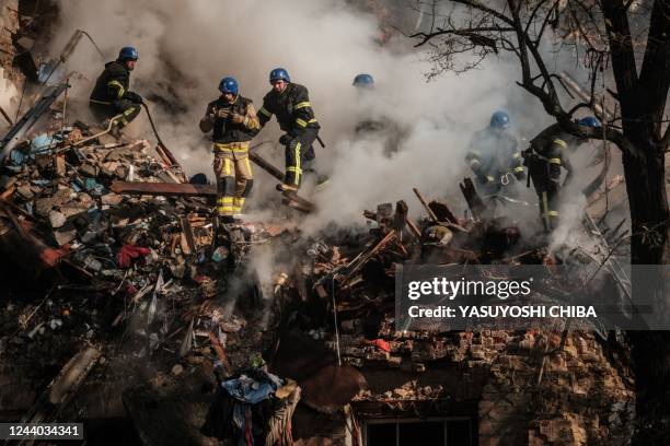 Ukrainian firefighters works on a destroyed building after a drone attack in Kyiv on October 17 amid the Russian invasion of Ukraine. - Ukraine...