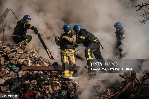 Ukrainian firefighters works on a destroyed building after a drone attack in Kyiv on October 17 amid the Russian invasion of Ukraine. - Ukraine...