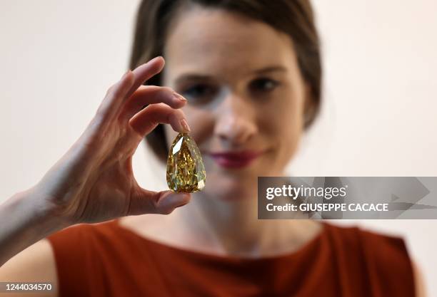 An employee holds up the "Golden Canary" brownish-yellow coloured diamond, weighing 303.10 carats, at Sotheby's in the Gulf emirate of Dubai on...