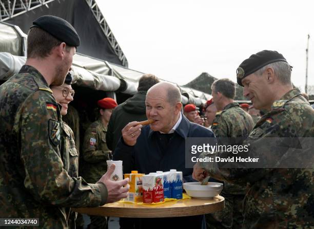 German Chancellor Olaf Scholz eats Bockwurst after his visite of the Bundeswehr army training center in Ostenholz on October 17, 2022 near...