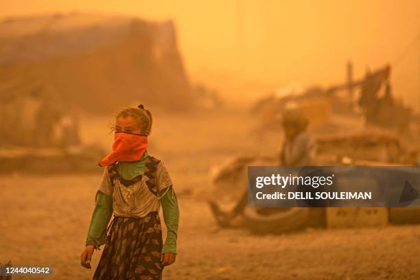 Girl covers her face amid a sandstorm at the Sahlat al-Banat camp for displaced people in the countryside of Raqa in northern Syria on October 17,...