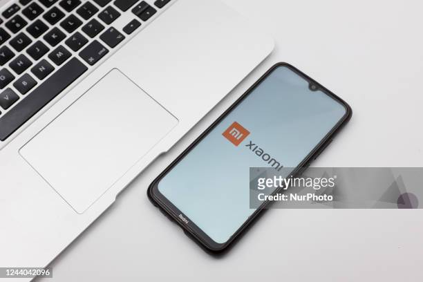 In this photo illustration a Xiaomi logo seen displayed on a smartphone screen on a desk next to a Macbook in Athens, Greece on October 17, 2022.