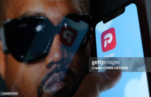 This illustration photo shows the Parler social network app logo on a cell phone screen with a picture of US rapper Kanye West in the background in...