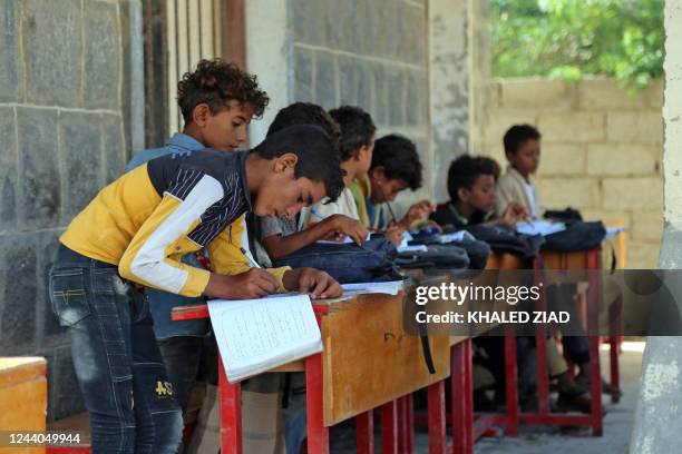 Yemeni children attend class outdoors in a heavily damaged school on the first day of the new academic year in Yemen's war-torn western province of...