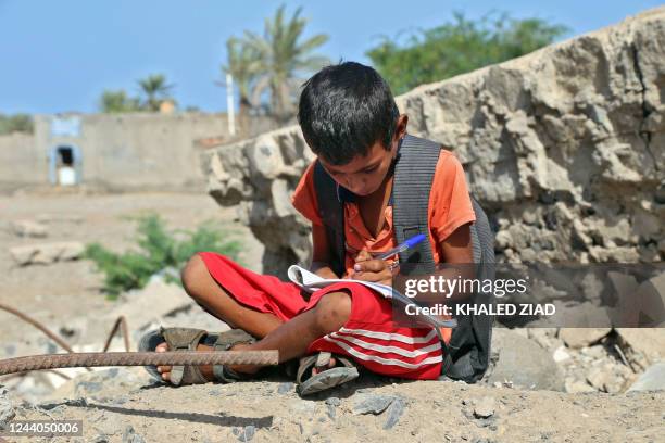 Yemeni children attend class outdoors in a heavily damaged school on the first day of the new academic year in Yemen's war-torn western province of...