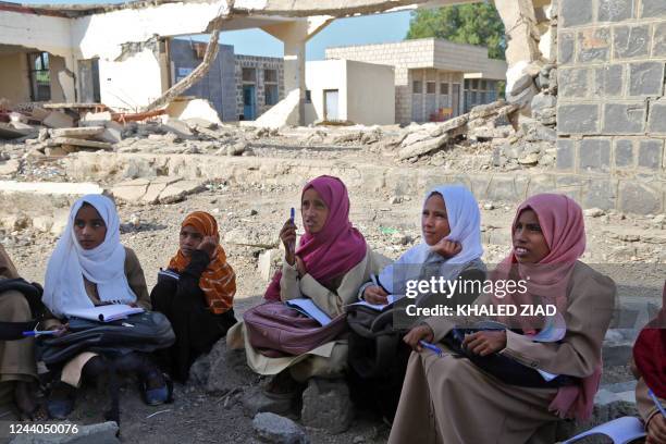 Yemeni children attend class outdoors in a heavily damaged school on the first day of the new academic year in Yemen's war-torn western province of...