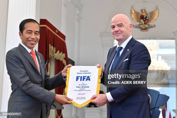 Gianni Infantino , president of football's world governing body FIFA, presents a souvenir to Indonesias President Joko Widodo during a joint press...