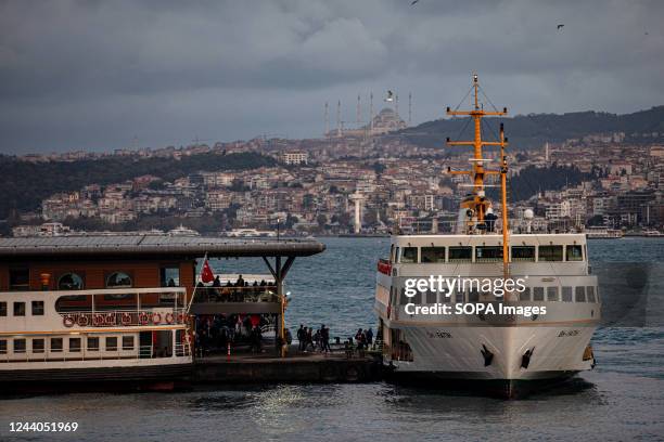 The passengers are seen boarding a ferry that stopped at the Karakoy city lines ferry port with Camlica Mosque in the background during cloudy...