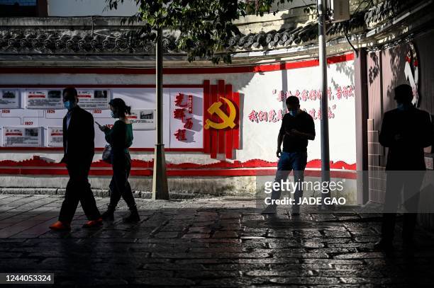 People walk past a wall on the history of the Communist Party of China at an alley in Zunyi, in China's southwestern Guizhou province on October 18,...