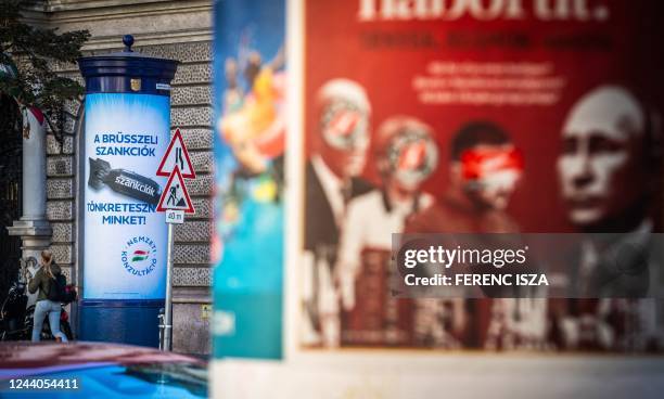 Woman passes by a poster depicting a bomb reading "We are being punished by the Brussels sanctions", in Budapest on October 18, 2022. - Hungary on...