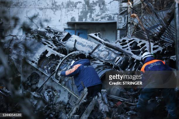 Russian Emergencies personnel remove the wreckage of a Sukhoi Su-34 military jet off its crash site in the courtyard of a residential area in the...