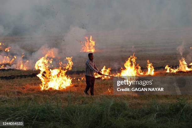 Farmer burns stubble after harvesting soyabean crop in his field on the outskirts of Bhopal on October 18, 2022.