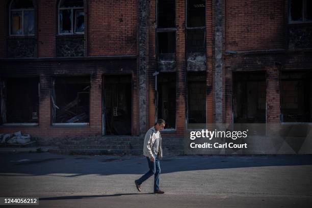 Man walks past a building believed to have been used by Russian occupying forces to torture local residents, on October 18, 2022 in Kozacha Lopan,...