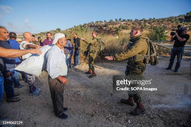 Israeli soldiers seen standing guard at the gate of the Israeli Elon Moreh settlement after it was opened, while Palestinian farmers making their way...