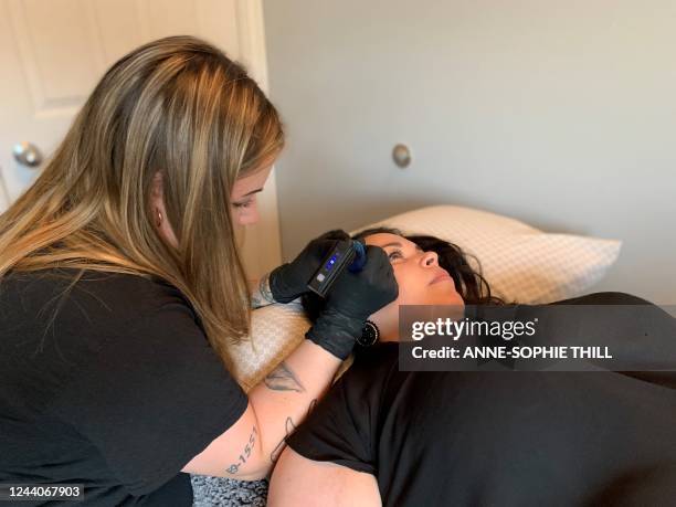 Inuit tattoo artist Kyra Kilabuk tatoos Micheline Kilabuk-Cote's temples on July 28, 2022 in Iqaluit, Nunavut, Canada. V-shapes on temples, dots on...