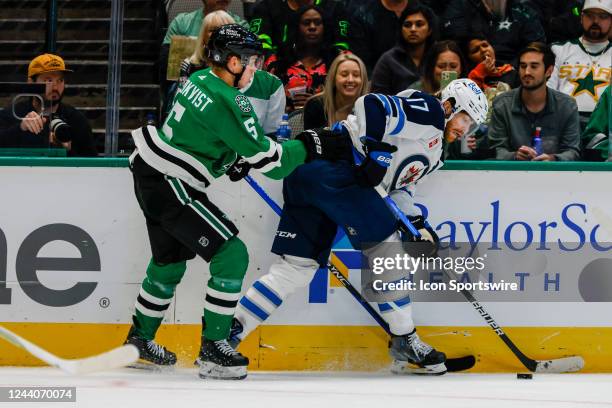 Dallas Stars defenseman Nils Lundkvist and Winnipeg Jets center Adam Lowry battle for the puck along the boards during the game between the Dallas...