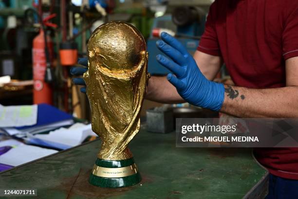 Worker poses on a table an almost finished replica of the FIFA World Cup trophy, for the FIFA World Cup Qatar 2022, at the Italian trophy and medal...