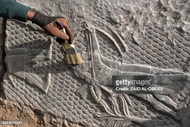 An Iraqi worker excavates a rock-carving relief recently found at the Mashki Gate, one of the monumental gates to the ancient Assyrian city of...