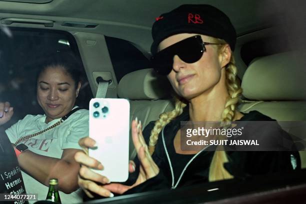 Model and actress Paris Hilton uses her mobile phone upon her arrival at the airport in Mumbai on October 19, 2022.