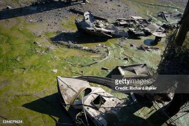 Sunken derelict boats sit in low-tide river mud and silt at Brentford Ait, on 18th October 2022, in London, England.