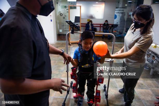 David Zabala, an 8-year-old boy with cerebral palsy, is assisted by physical therapists during a rehabilitation session with the robotic exoskeleton...