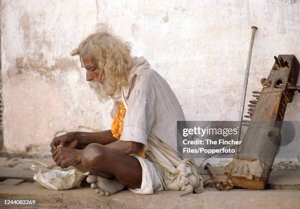 An elderly man with his ancient sitar eating on the streets of Kathmandu, Nepal, circa 1969.