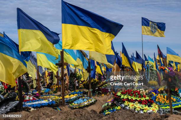Ukrainian flags fly above the graves of soldiers killed in action following the Russian invasion earlier this year, on October 19, 2022 in Kharkiv,...