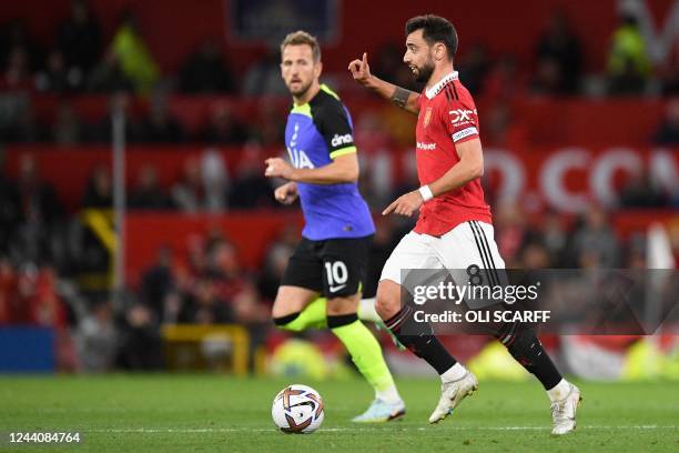 Manchester United's Portuguese midfielder Bruno Fernandes gestures as he runs with the ball next to Tottenham Hotspur's English striker Harry Kane...