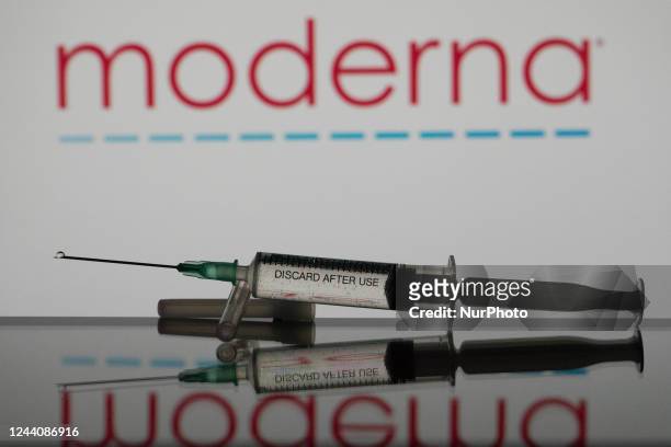 In this photo illustration a covid-19 vaccine is seen with the Moderna logo in the background.