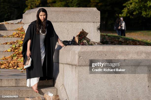 An Asian woman graduate from Imperial College London rests sore feet after celebrating her education success with friends and families beneath the...