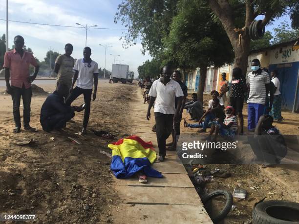 Graphic content / TOPSHOT - A body covered by a Chadian flag is shown by demonstrators in NDjamena on October 20, 2022 during a protest. - Five...