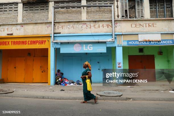 Woman walks in front of closed shops in the central business area of Accra, on October 20, 2022. - Traders in Ghana's capital Accra closed their...