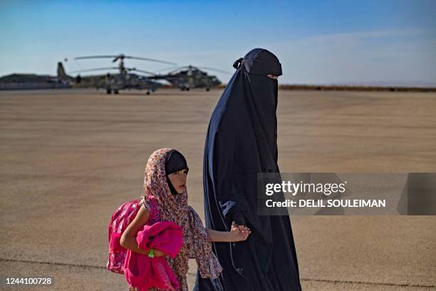 Woman accompanies a child, one of 38 from families of suspected Islamic State group, toward a plane before being repatriated to Russia, at the...