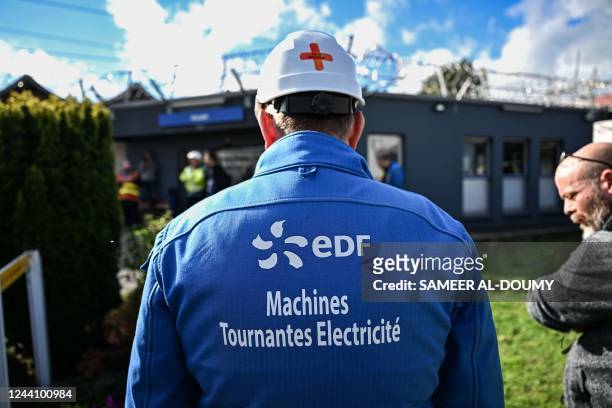 This photograph taken on October 20, 2022 shows an employee of French multinational electric utility company EDF wearing a blue working gear with the...