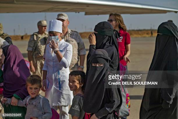 Group of children, among 38 from families of suspected Islamic State group, are protected by Russian soldiers, as they board a plane before being...