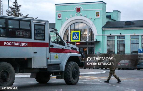 Russian serviceman walks past a truck of the Russian National Guard parked near Dzhankoi's railway station in Crimea on October 20, 2022. - Russian...