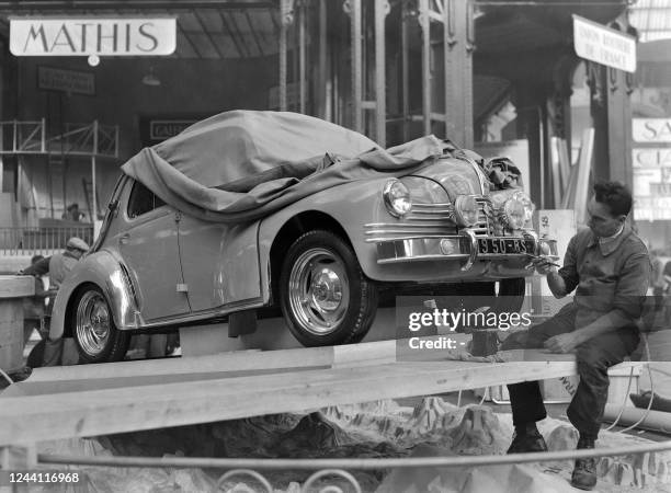 Man repaints the license plate of a Renault 4CV Grand Luxe covered with a tarpaulin, on Ocotber 05, 1949 before the opening of the 36th Paris Motor...
