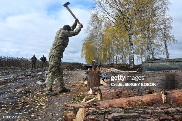 Soldier of the National Guard of Ukraine chops firewood in the northern liberated territories of Kharkiv region on October 21 amid the Russian...