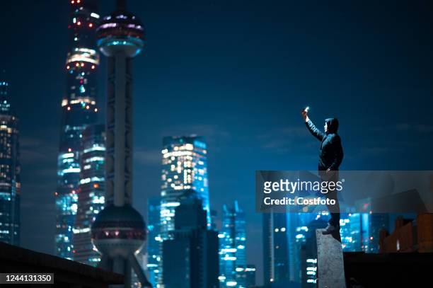 Citizen takes a photo of Lujiazui high-rise buildings and other landmarks at night on the old roof of the North Bund in Shanghai, China, Oct 19, 2022.